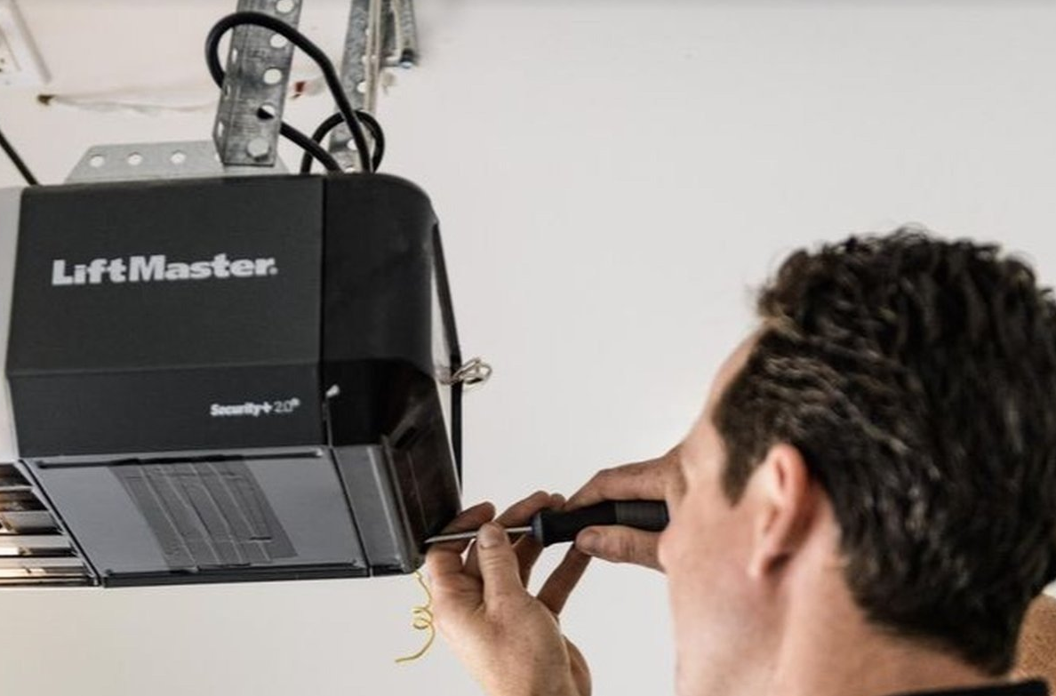 Certified technician fixing a garage door opener motor and testing safety sensors in Sunbury, Ohio